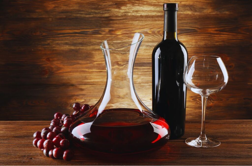 carafe a vin et une bouteille de vin rouge avec un verre a pied